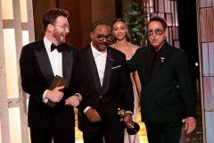 HOLLYWOOD, CALIFORNIA - MARCH 15: In this handout photo provided by The Academy, presenters Chris Evans (L) and Robert Downey Jr. (R) walk off stage as Ryan Coogler carries the Writing (Original Screenplay) award for "Sinners" during the 98th Oscars at Dolby Theatre on March 15, 2026 in Hollywood, California. (Photo by Al Seib / The Academy via Getty Images)